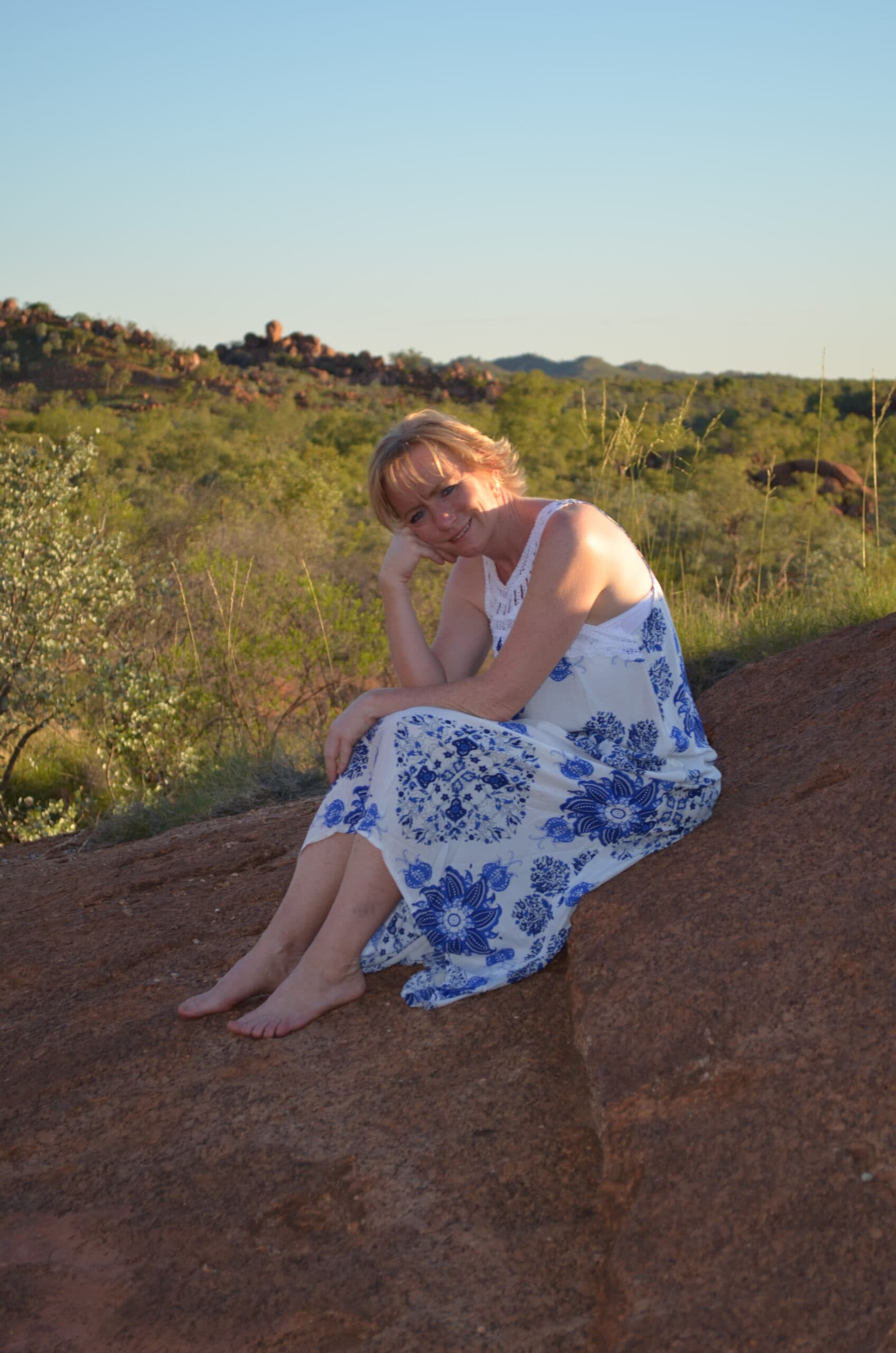 Katrina Gall sitting outdoors on red rock, reflecting